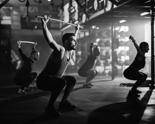 black-white-photo-group-athletes-exercising-with-weight-bars-sports-training-gym_637285-2485